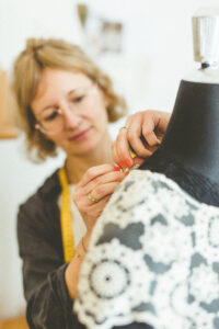 Kathleen Tischer arbeitet an den Details eines Kleides auf einer Schneiderpuppe
